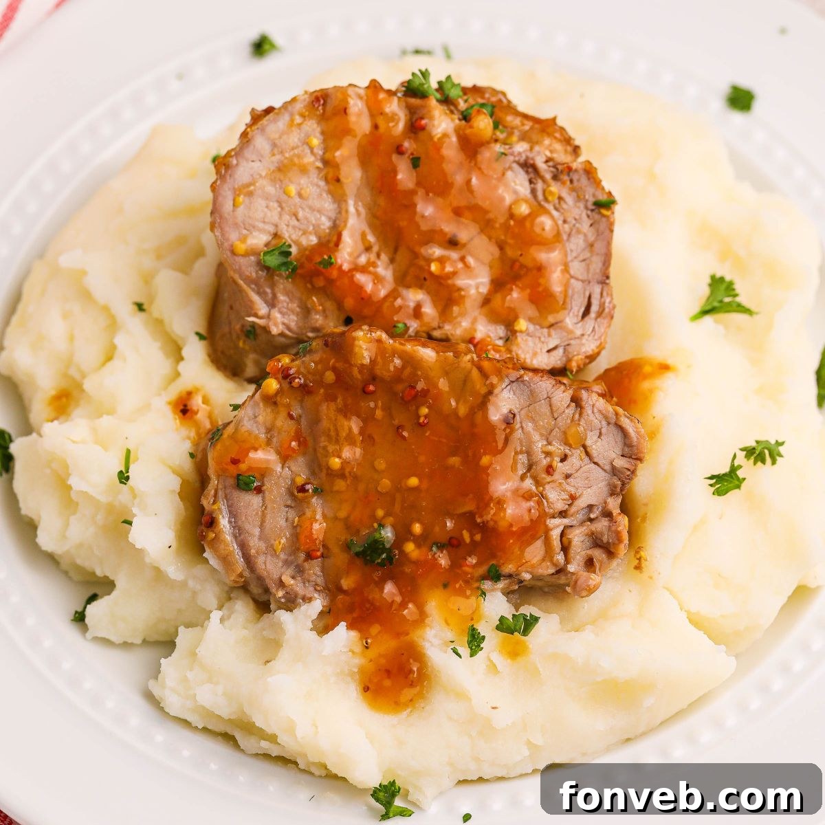 Crock Pot Apricot Pork Tenderloin sliced and sitting on top of mashed potatoes on a plate