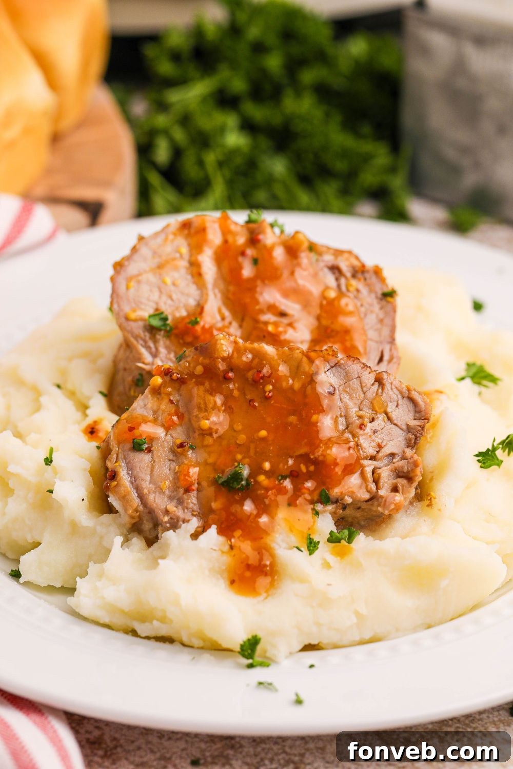 pork tenderloin apricot glaze on top on top of a pile of mashed potatoes on plate on counter