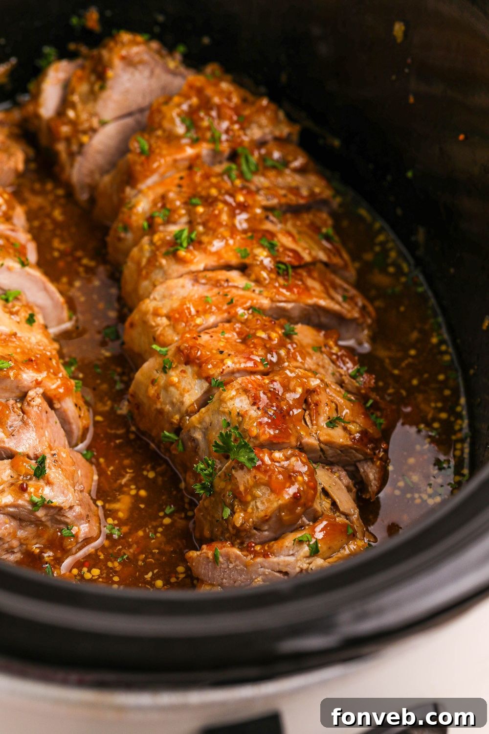 sliced apricot pork in a slow cooker with fresh herbs on top