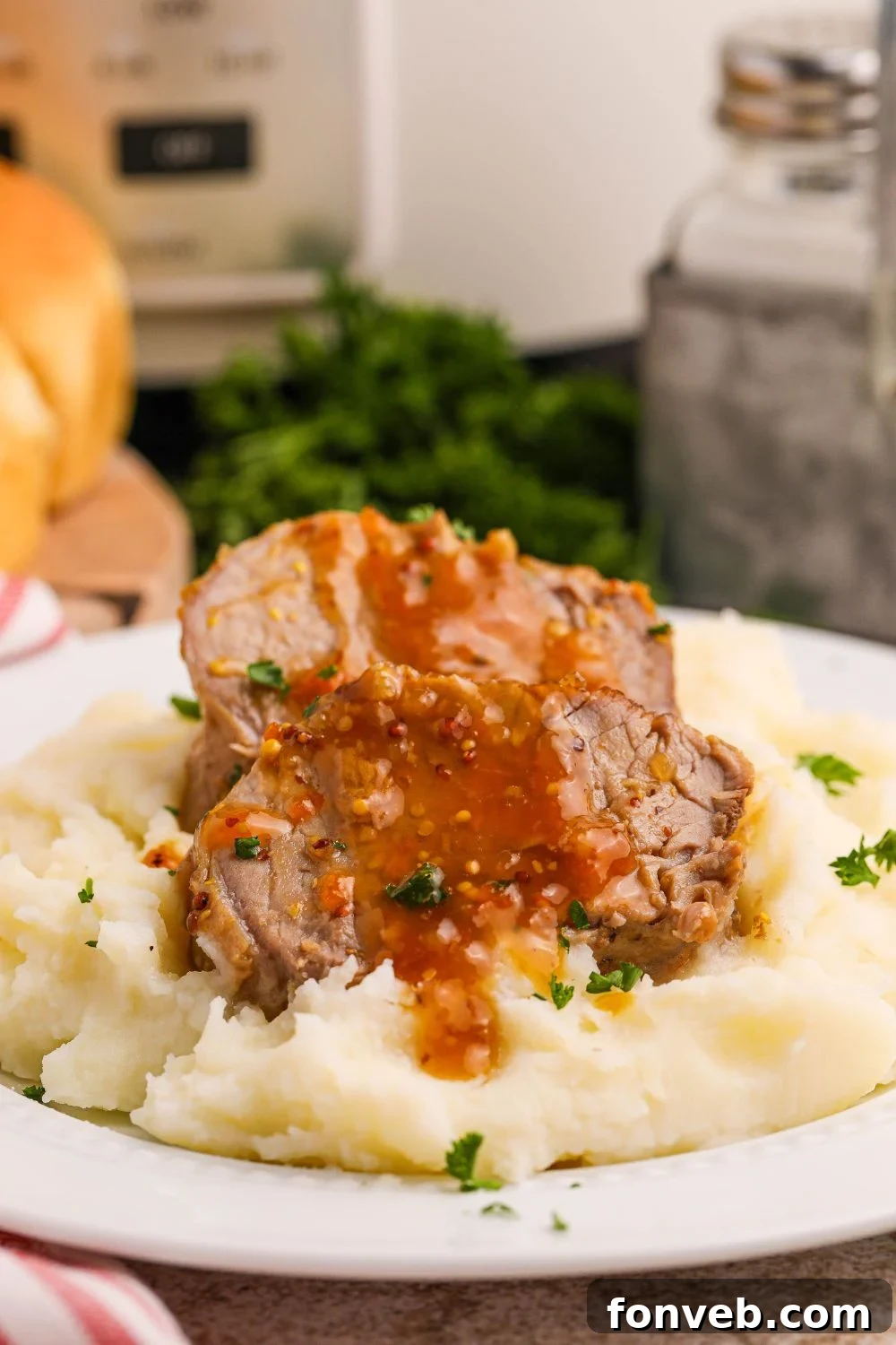 pork tenderloin apricot glazed sitting on top of mashed potatoes on a plate