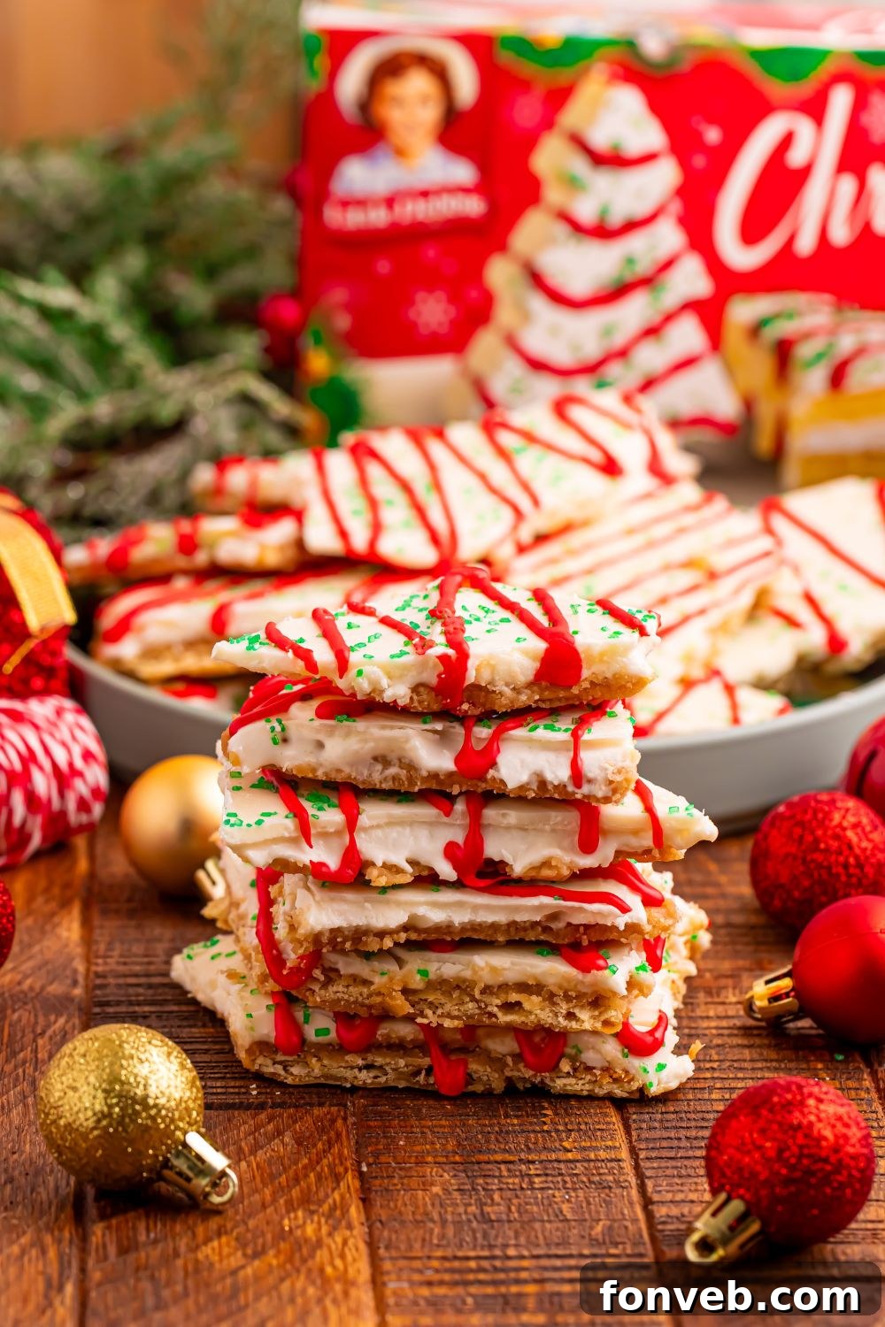 Addictive Little Debbie Christmas Tree Cake Toffee Bark 13 Christmas Tree Crack stacked in front with a bowl of more crack behind it and holiday decorations around the plate