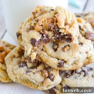 Chocolate Chip Toffee Cookies stacked on top of each other on table with a glass of milk on table