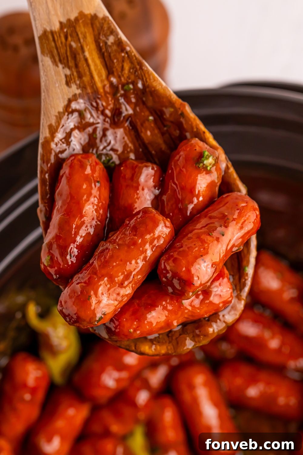 Slow Cooker Mississippi Lil Smokies in slow cooker with a wooden spoon with some smokies on it