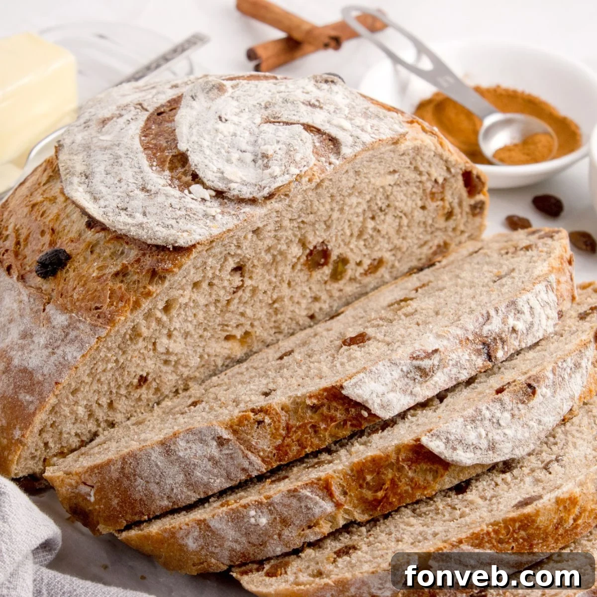 Cinnamon raisin bread on table that is half sliced into slices 