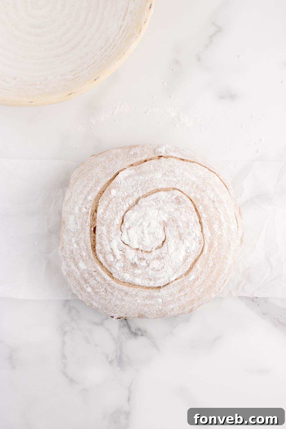 scored cinnamon raisin bread on table in raw dough form 