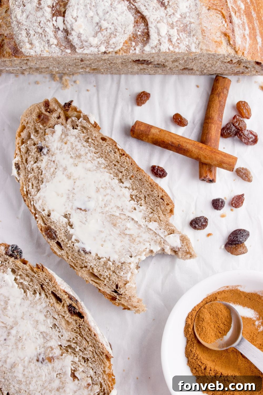 cinnamon raisin bread on table with butter spread on top and ingredients around it on table