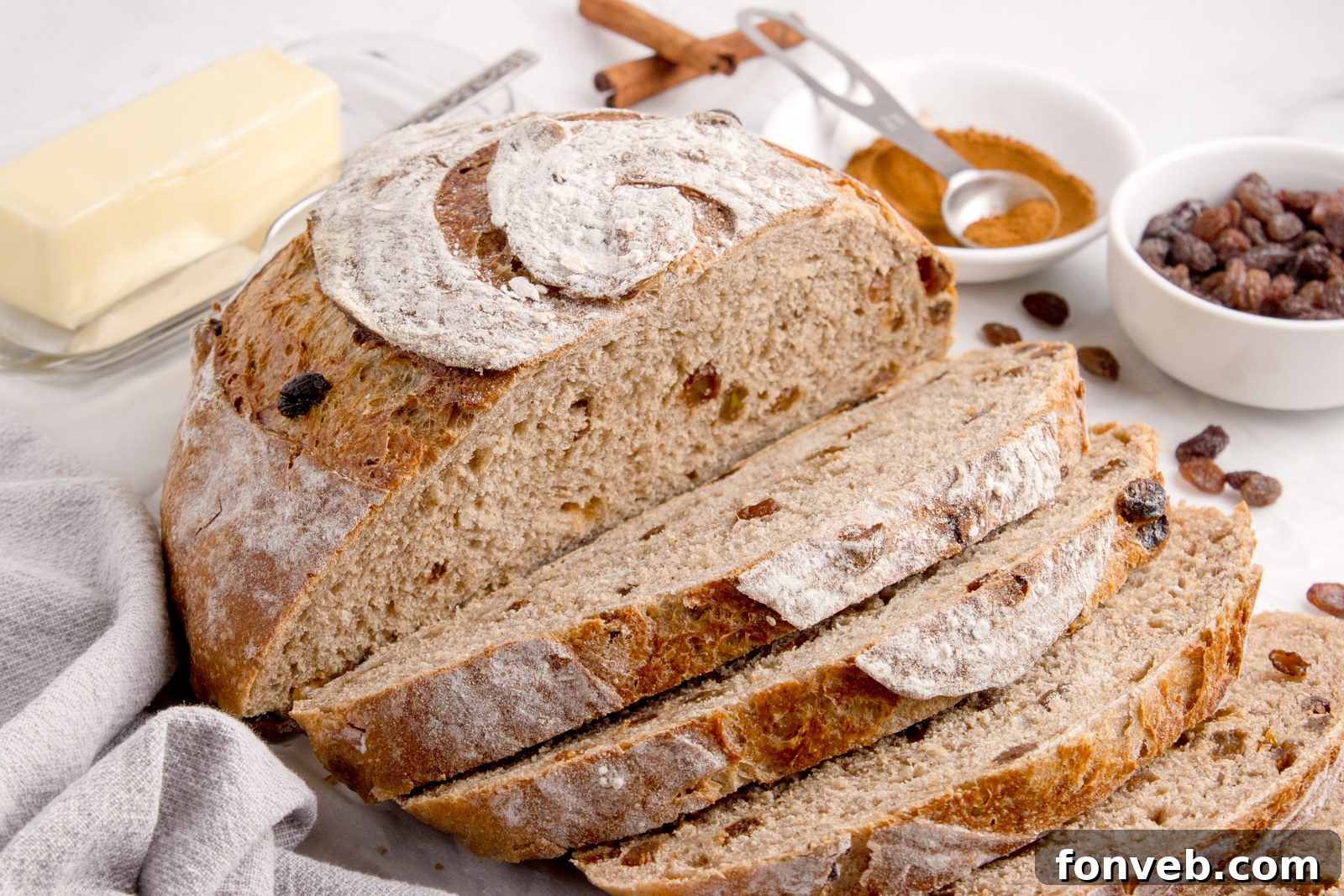 cinnamon raisin dutch oven bread sliced and placed on table with two cinnamon sticks sitting in front of loaf