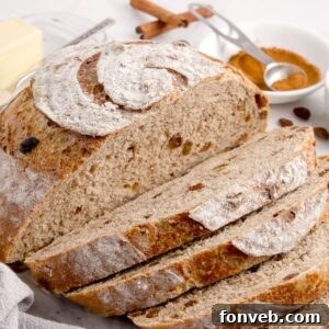 Cinnamon raisin bread on table that is half sliced into slices
