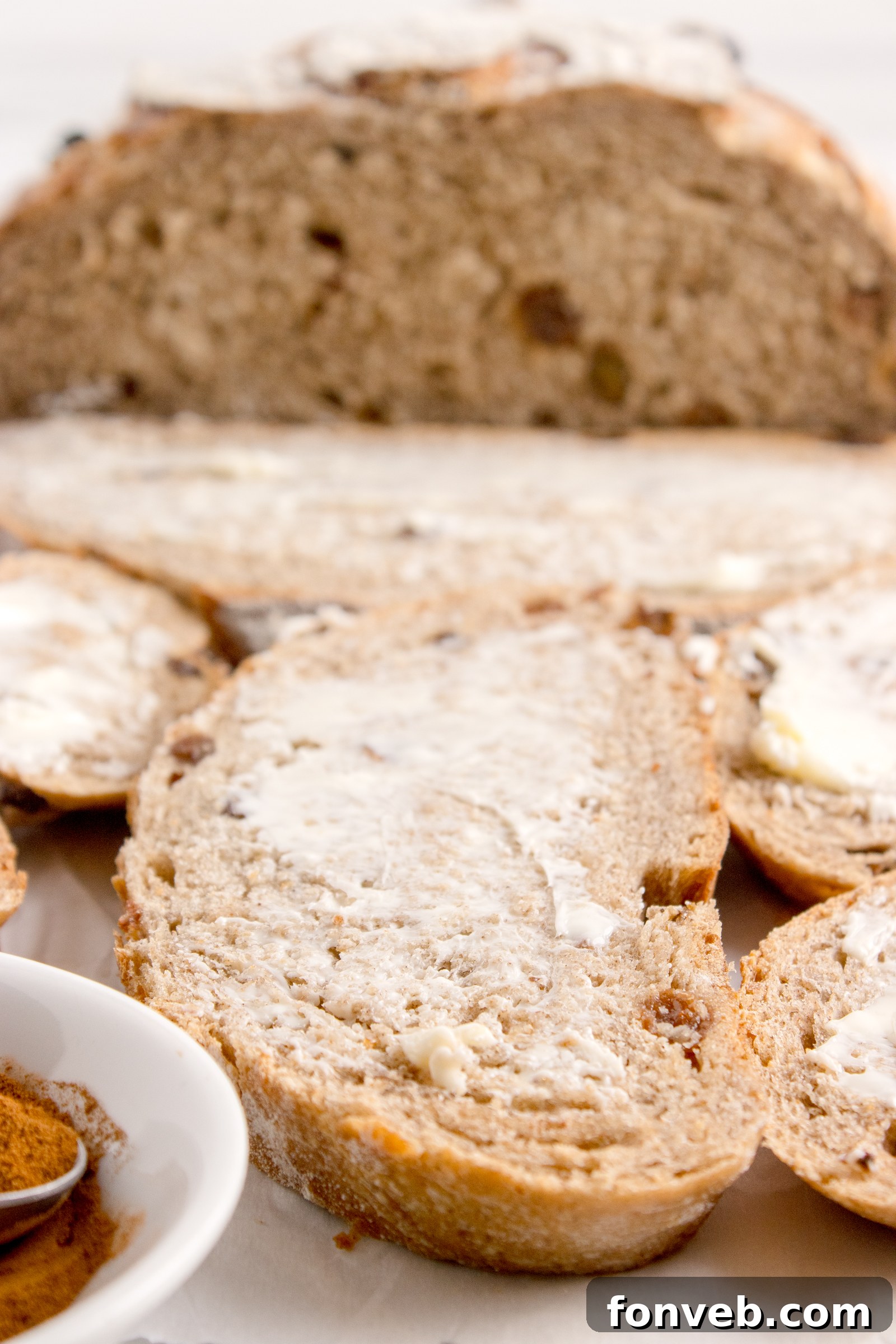 Cinnamon raisin bread on table with a piece covered in butter 