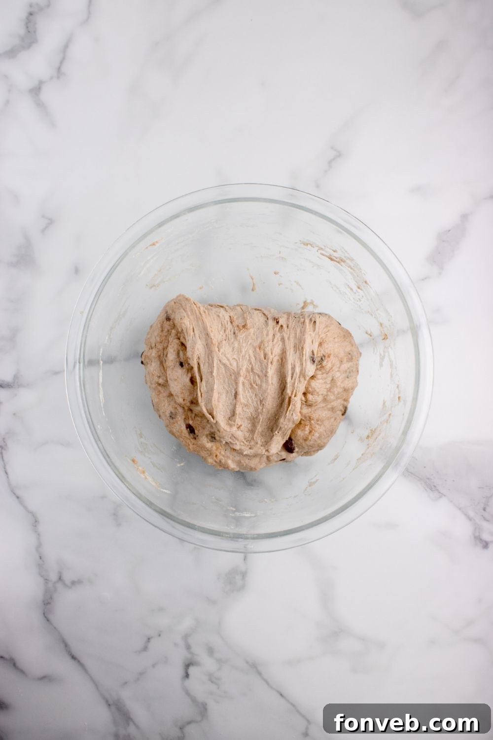 dough of cinnamon raisin bread in a glass bowl on table 