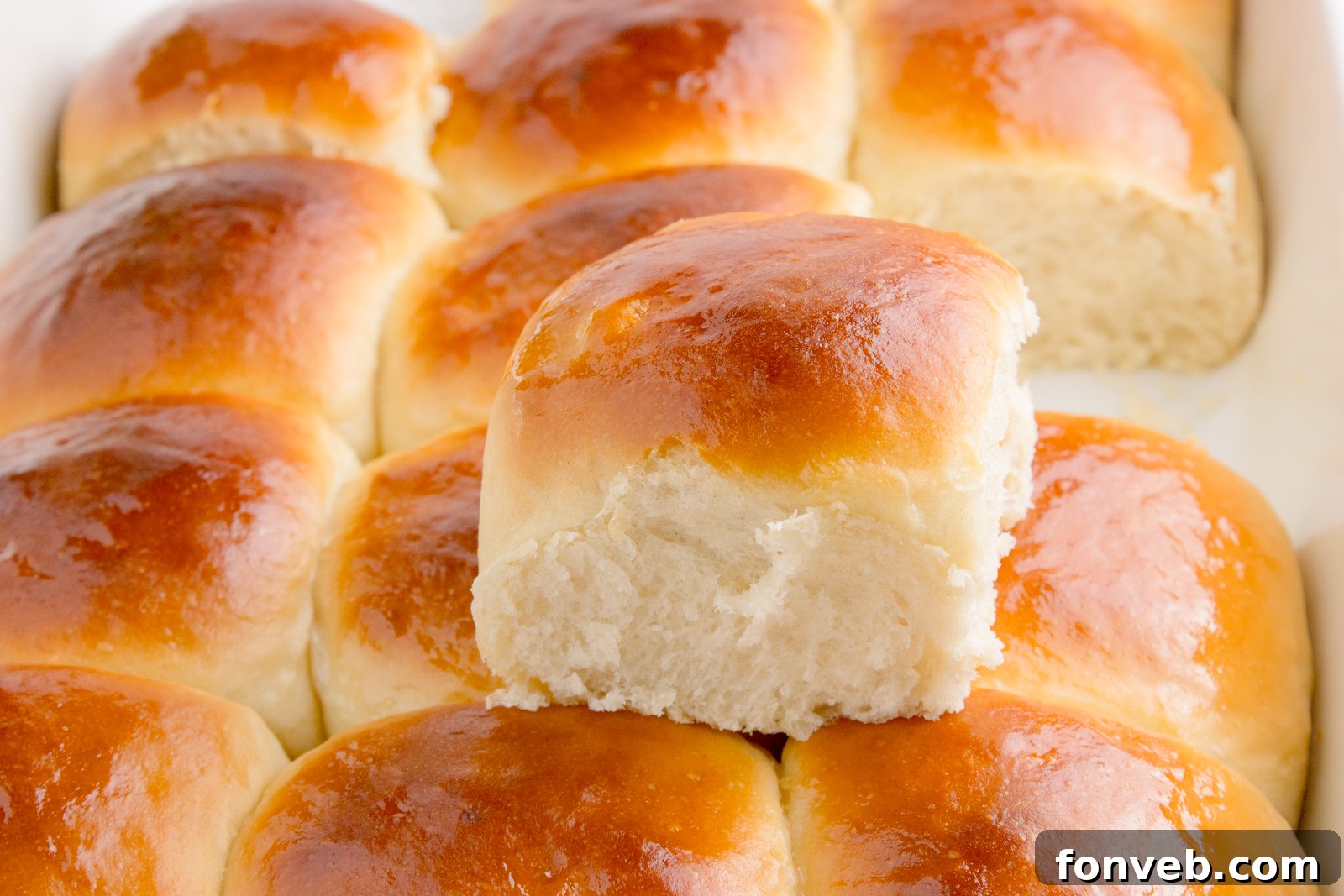 Tropical Dinner Buns 3 Hawaiian dinner rolls in a baking dish with one removed sitting on top