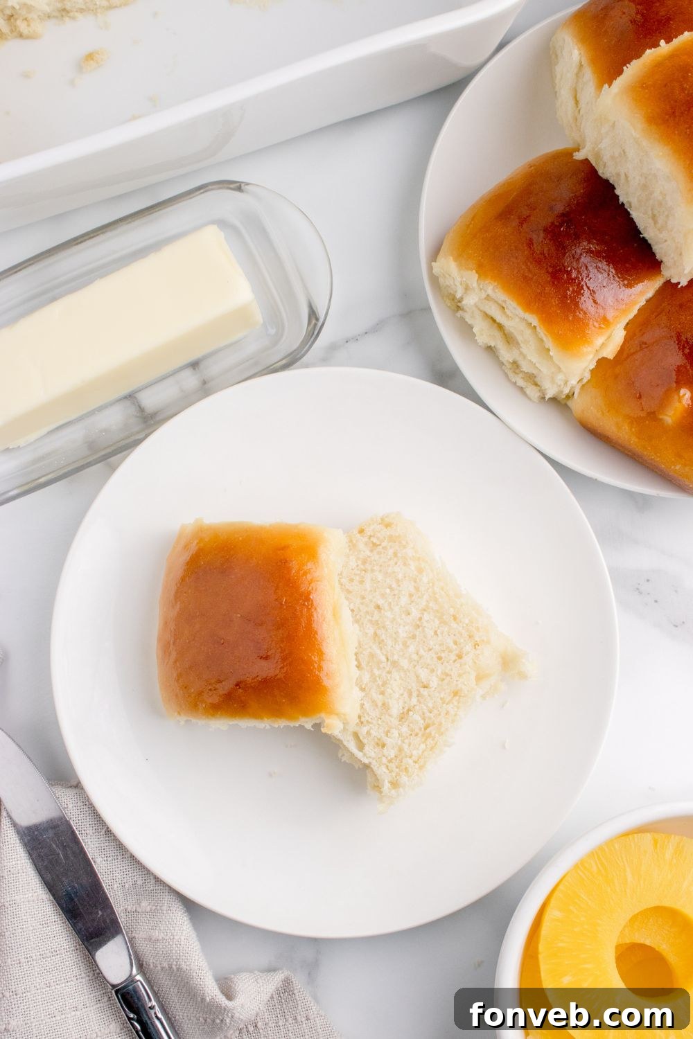 Tropical Dinner Buns 21 plate of dinner rolls on table, and a slice of bread on plate with a stick of butter on side