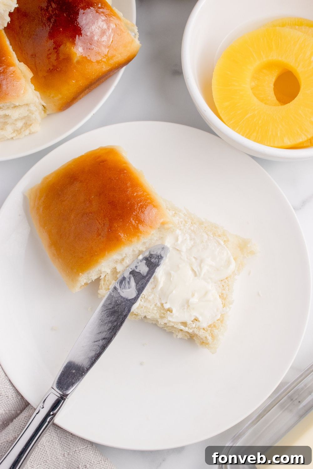 Tropical Dinner Buns 22 dinner roll with butter spread on top of it on plate