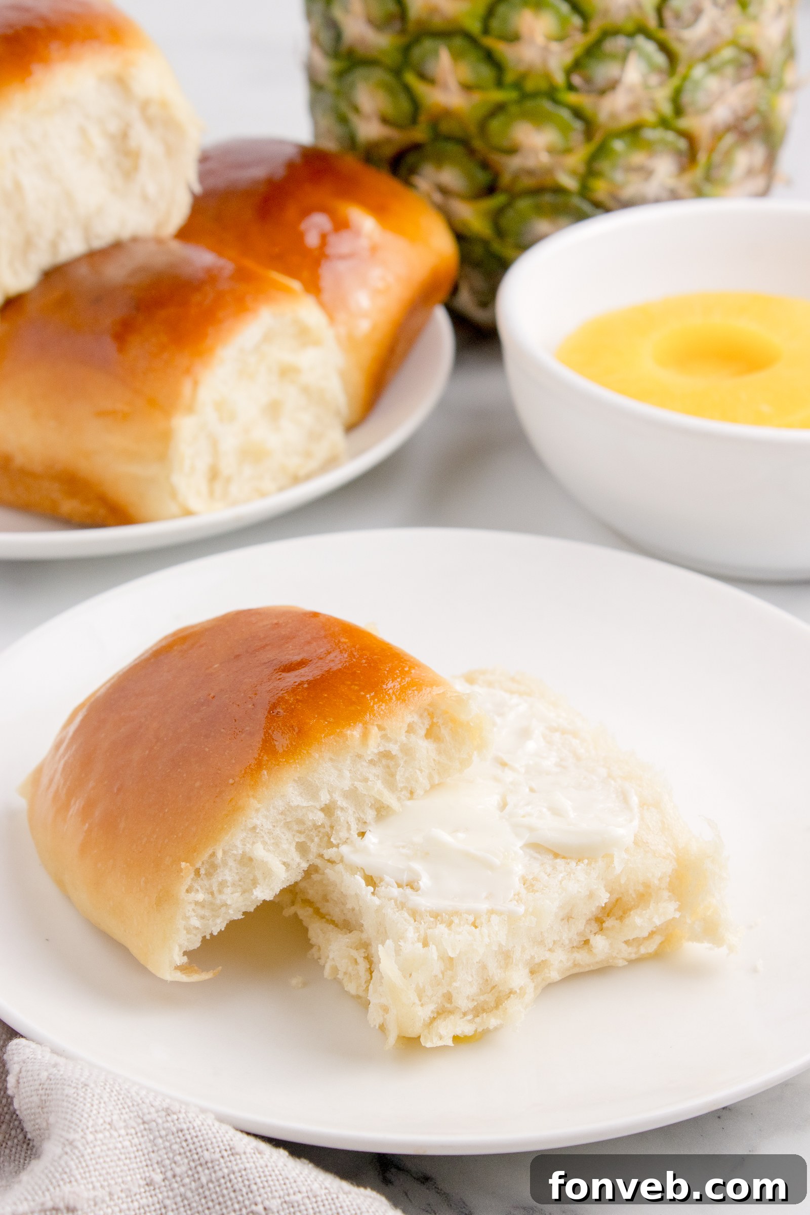 Tropical Dinner Buns 4 Hawaiian Dinner Roll on plate with it sliced in half and butter spread on it