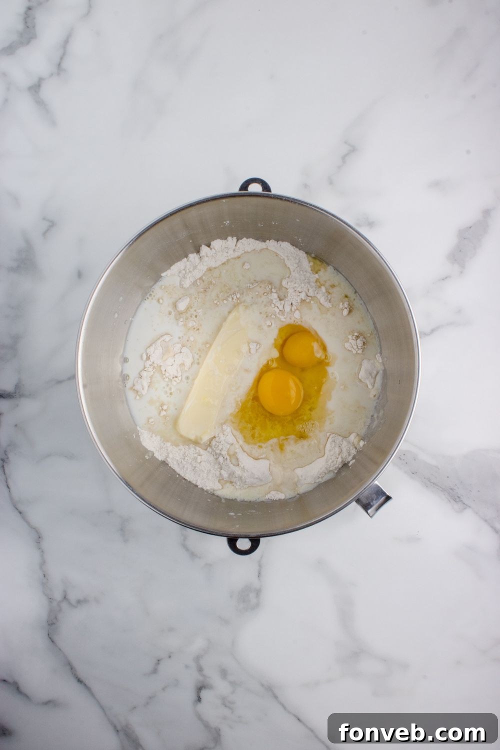 Tropical Dinner Buns 9 butter and eggs in a flour mixture in a mixing bowl on table for Hawaiian rolls