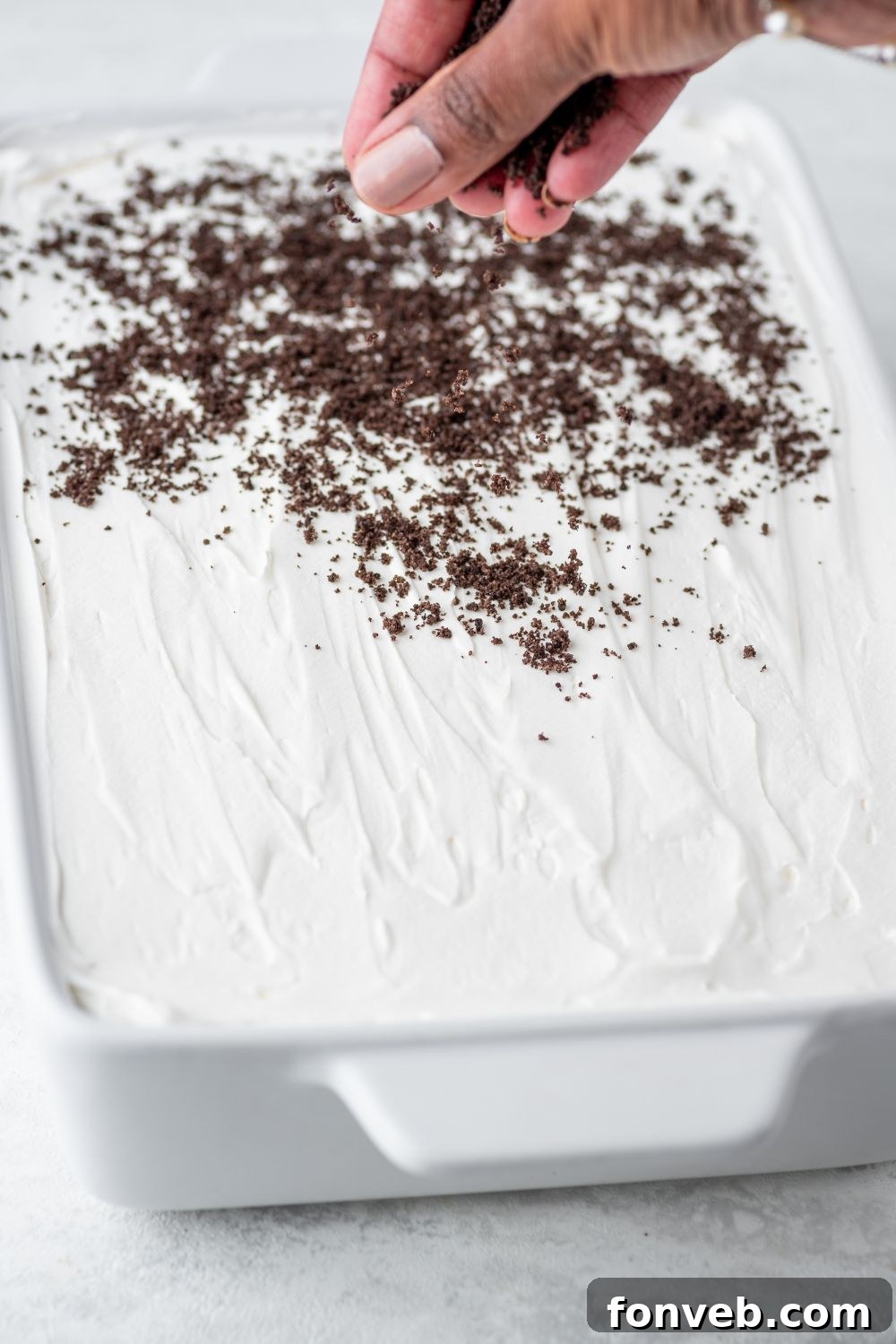 Ultimate Chocolate Oreo Delight 11 Crushed Oreo cookies being sprinkled generously over the top whipped cream layer of the Chocolate Oreo Lush, adding texture and an extra touch of Oreo goodness.