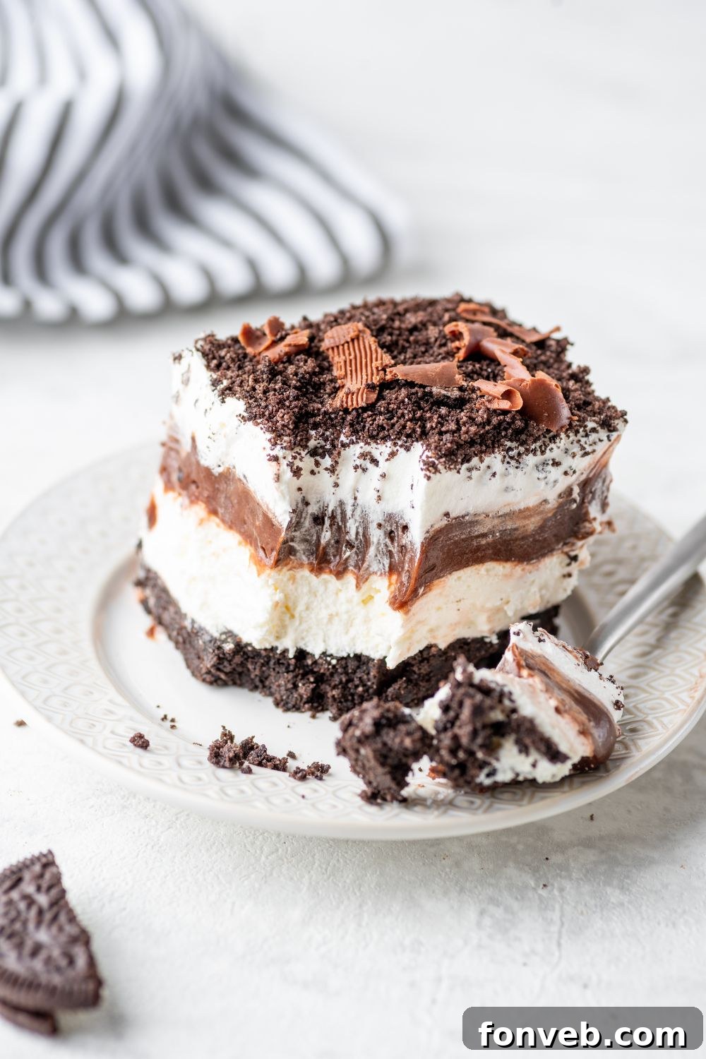 Ultimate Chocolate Oreo Delight 14 A slice of Chocolate Oreo Lush on a white plate, with a bite on the fork, emphasizing its creamy texture and rich chocolate flavor.