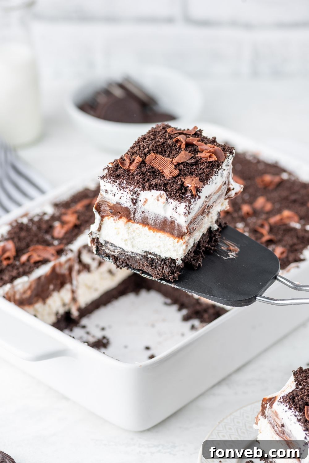 Ultimate Chocolate Oreo Delight 15 A slice of Chocolate Oreo Lush being carefully lifted out of the casserole pan with a spatula, showcasing the clean layers.