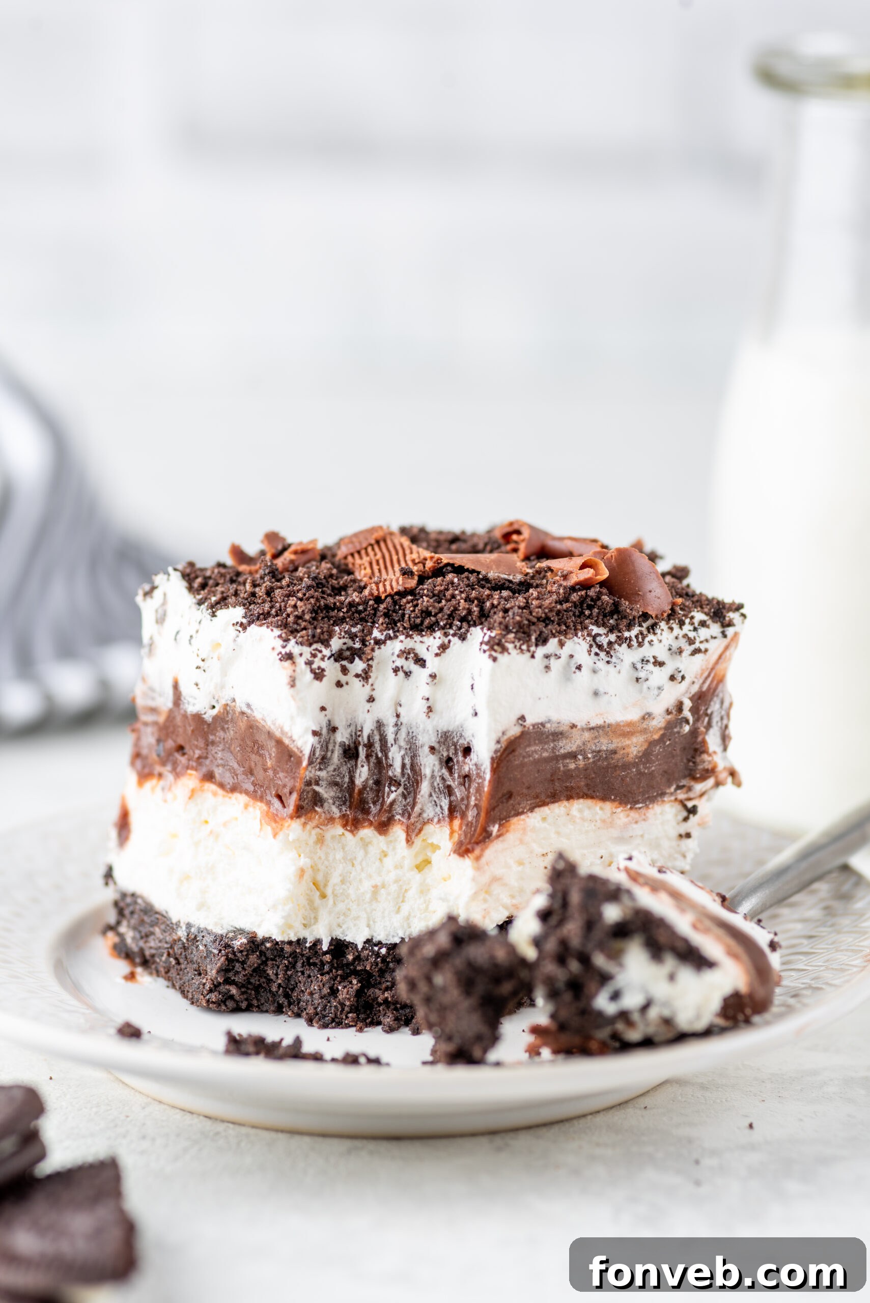 Ultimate Chocolate Oreo Delight 18 A single serving of Chocolate Oreo Lush on a plate with a piece missing, showing the delightful layers, ready to be eaten.