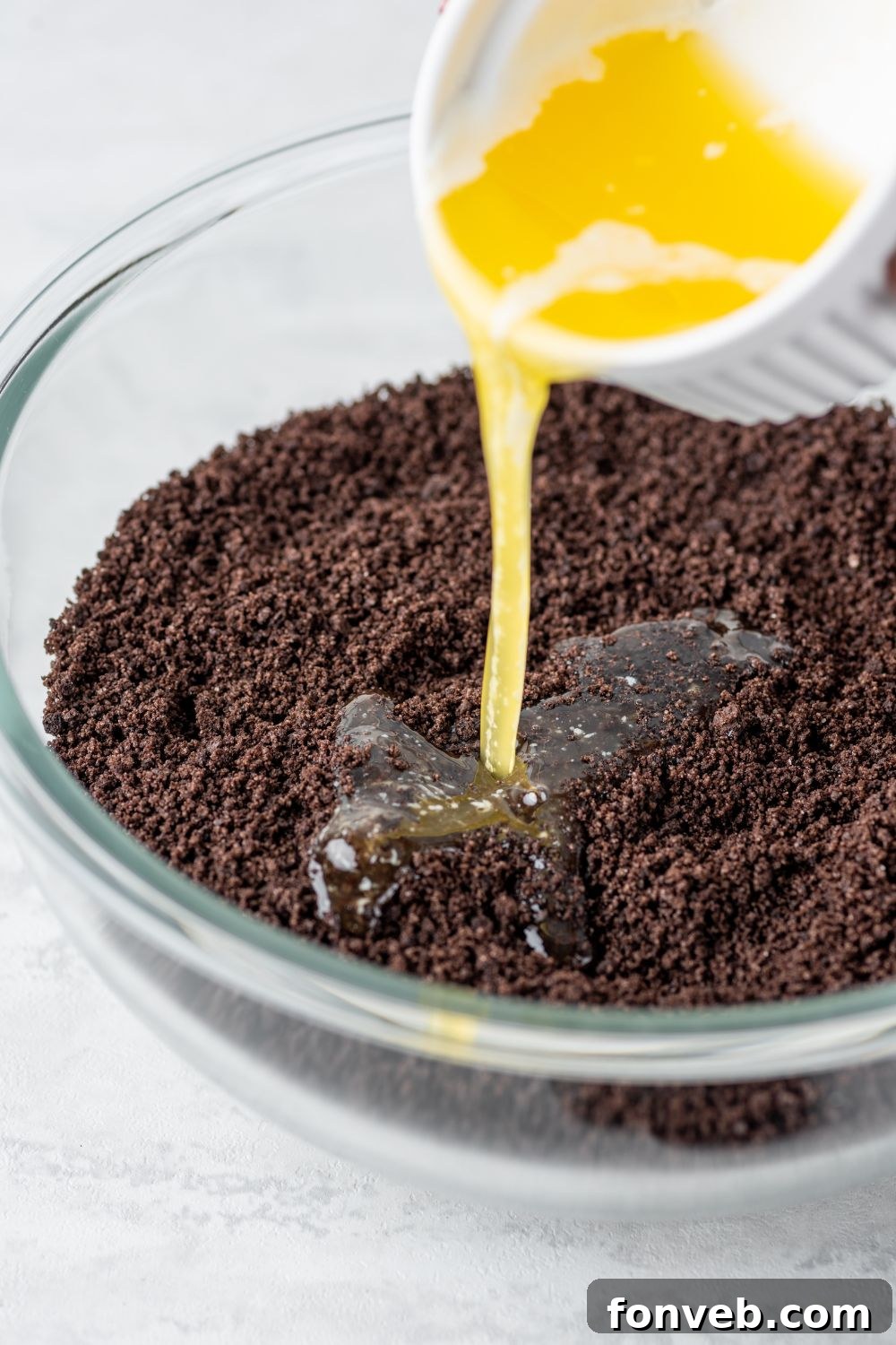 Ultimate Chocolate Oreo Delight 6 Melted butter being poured into a bowl of finely crushed Oreo cookies, ready to be mixed for the Chocolate Oreo Lush crust.