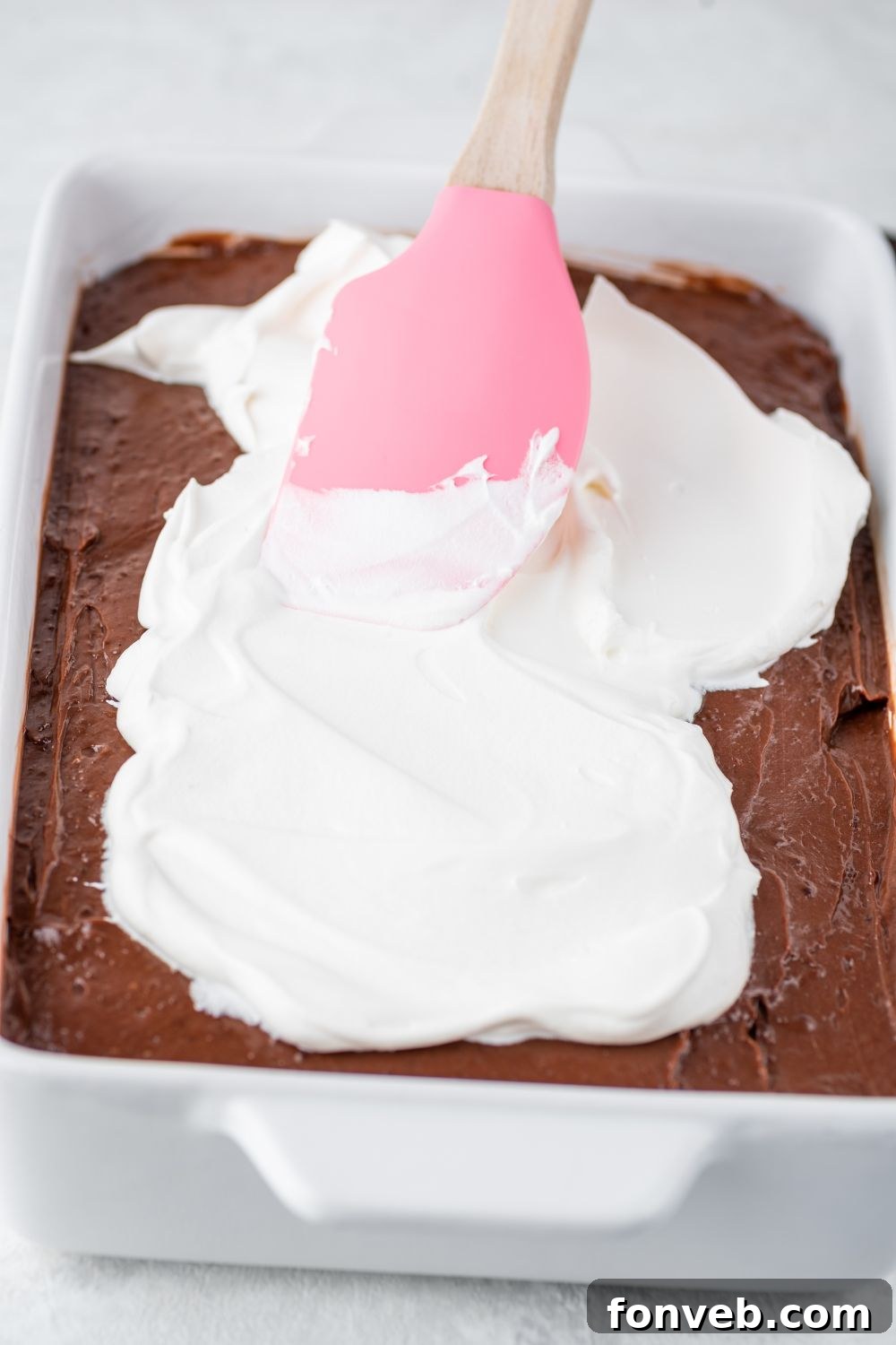 Ultimate Chocolate Oreo Delight 9 Light and fluffy whipped cream being gently spread as the final layer on top of the chocolate pudding, completing the beautiful layers of the Chocolate Oreo Lush.