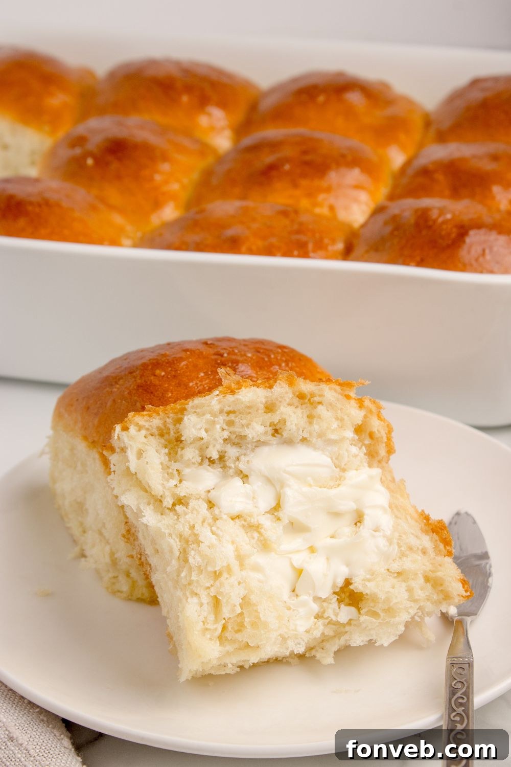 Pull Apart Rolls in a baking pan on counter with one cut in half spread with butter