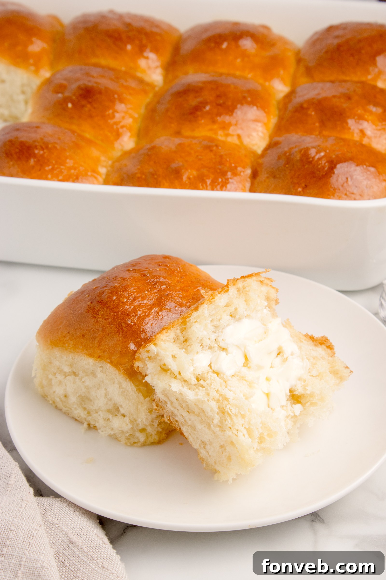 Pull Apart Dinner Rolls on a white plate with one cut in half and buttered