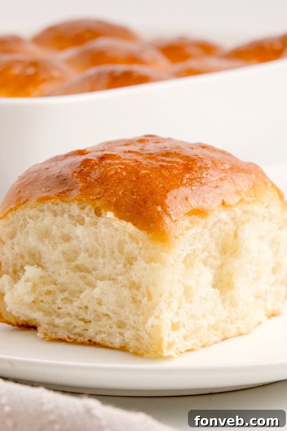 Pull Apart Roll on plate with the pan behind it with the rest of dinner rolls