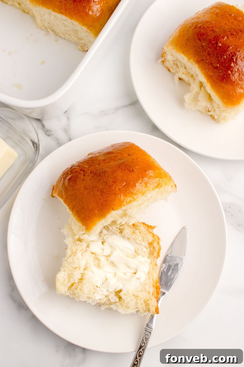 Pull Apart Dinner Rolls on plates with one cut in half and buttered