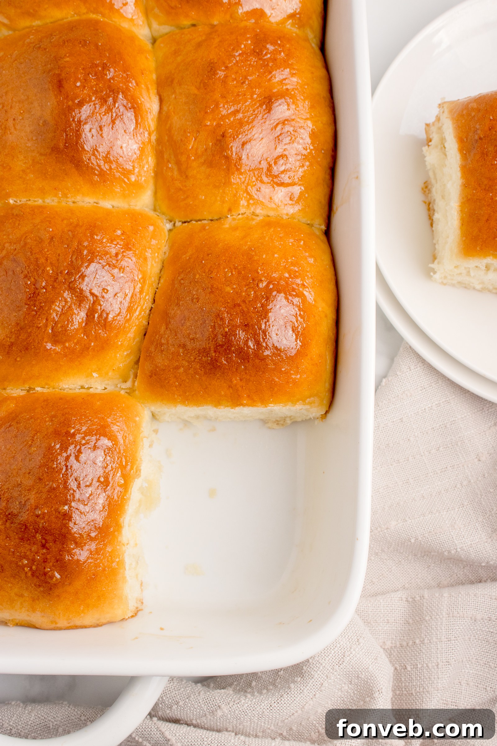 Pull Apart Dinner Rolls in a white baking dish with one removed