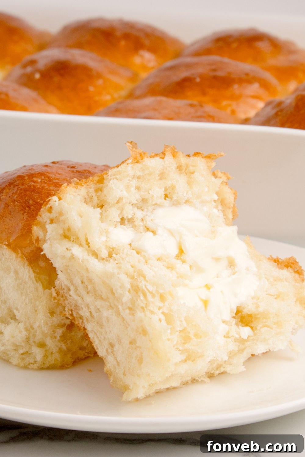 pull apart dinner rolls in a pan with one on a plate slathered with butter