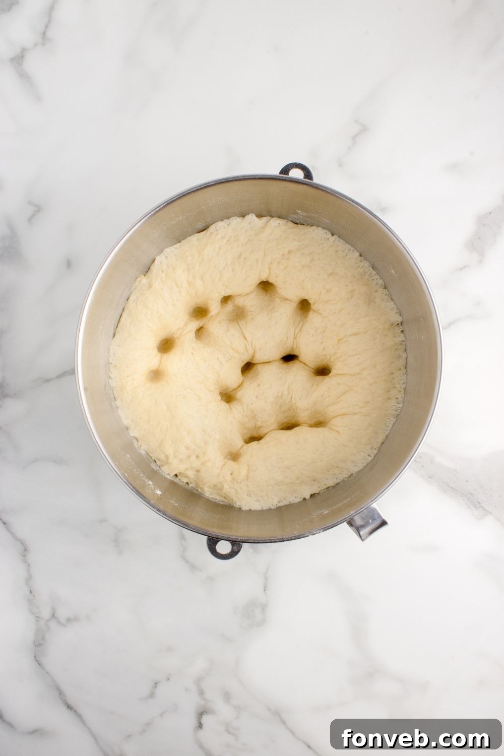risen dough for pull apart rolls in mixing bowl punched down with fingers