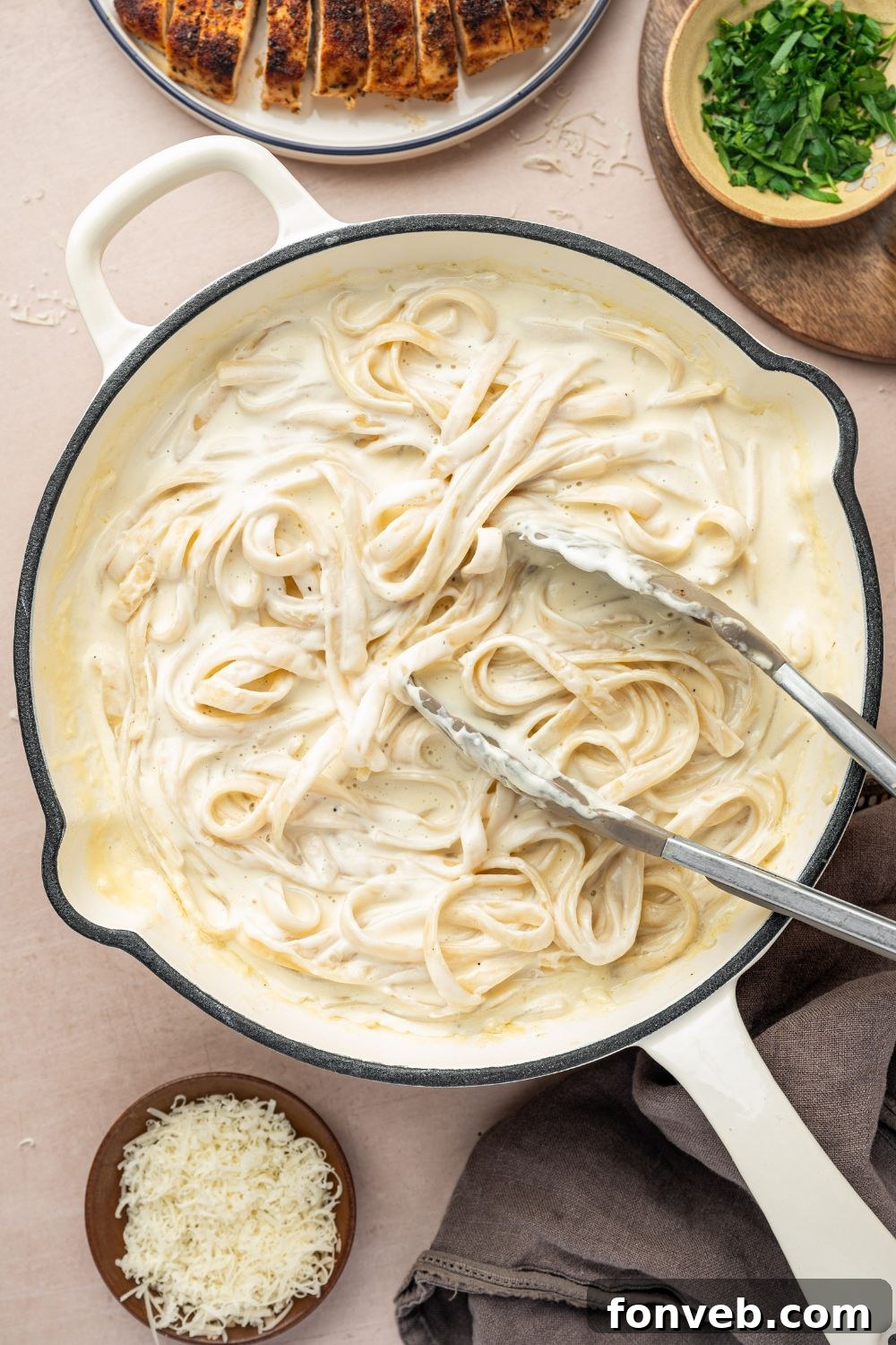Cajun Chicken Alfredo 13 alfredo noodles in a skillet with tongs sitting on top of the pasta
