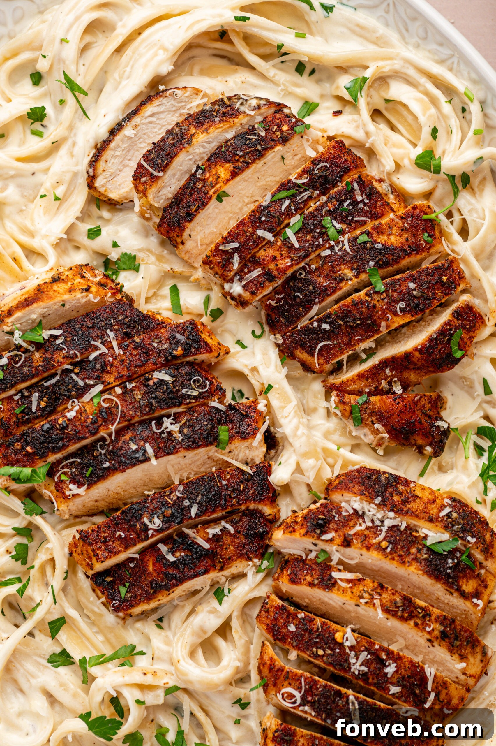 Cajun Chicken Alfredo 4 blackened chicken alfredo on a plate with parsley and grated parmesan cheese on top