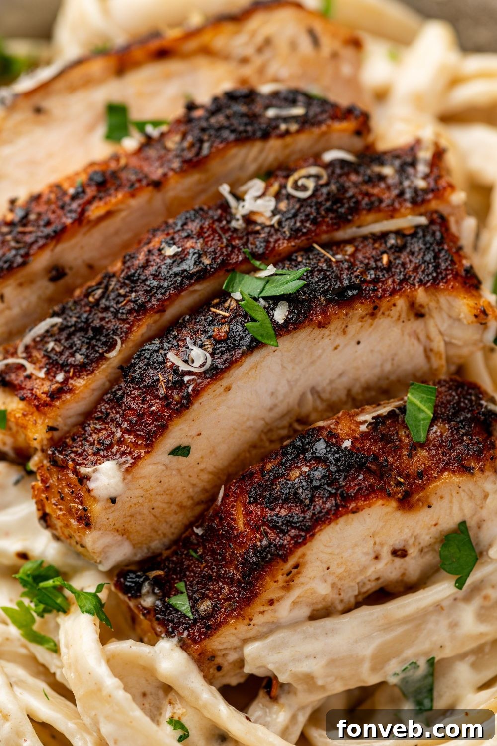 Cajun Chicken Alfredo 5 blackened chicken alfredo on a plate with parsley and grated parmesan cheese on top