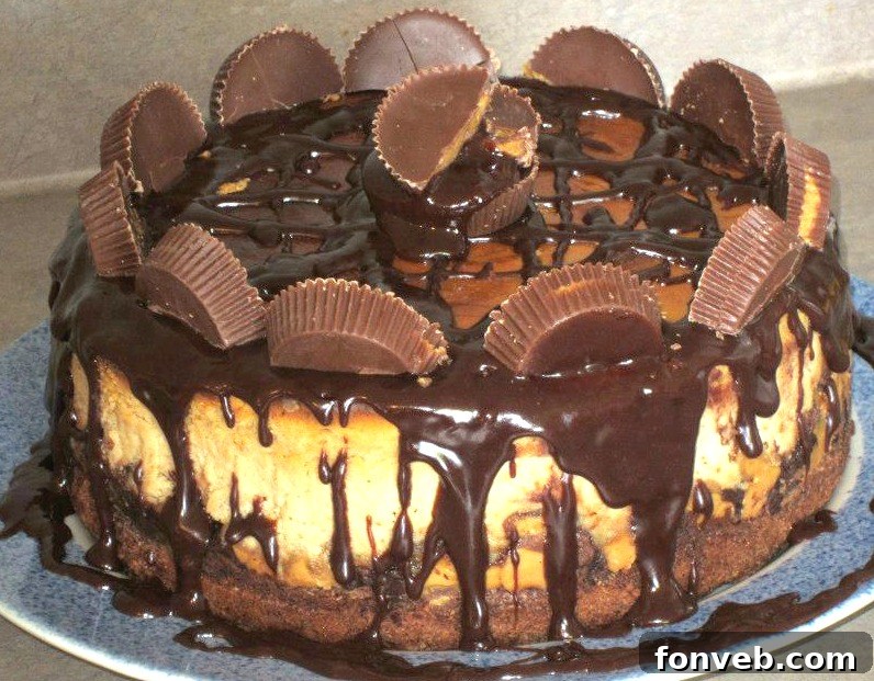 Close-up of a whole Reese's Peanut Butter Cup Cheesecake, topped with generous amounts of chopped Reese's candy.