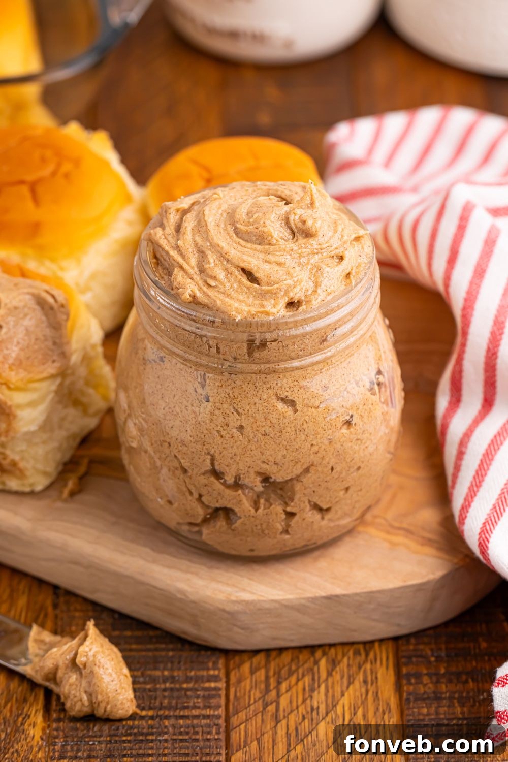 cinnamon spread in a jar with rolls and a towel around it on table