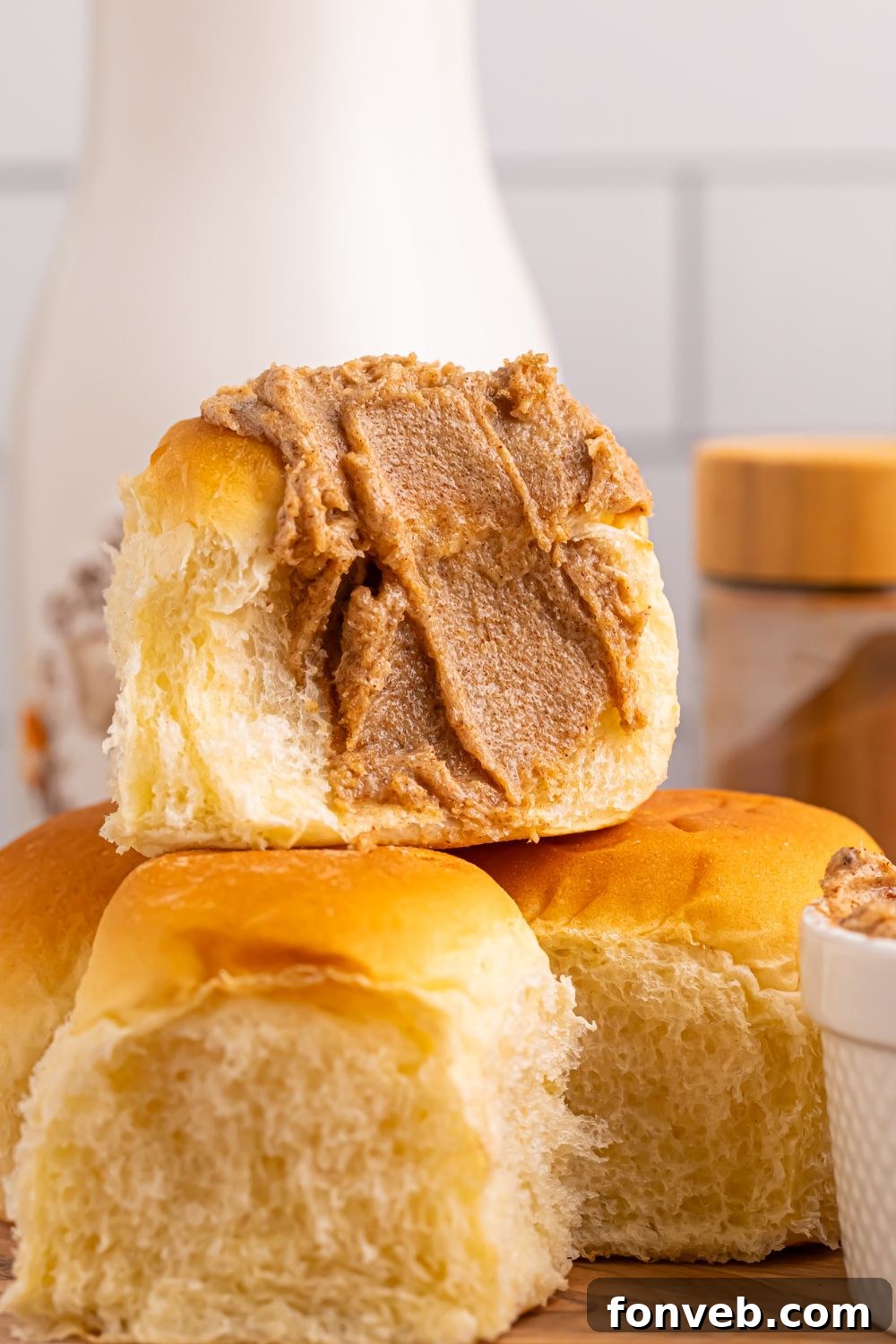 Brown Sugar Cinnamon Butter spread on a roll that is cut in half and stacked on top of more rolls 