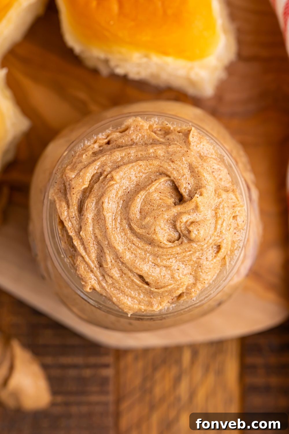overhead look of cinnamon butter in a glass jar sitting on wooden cutting board on table 