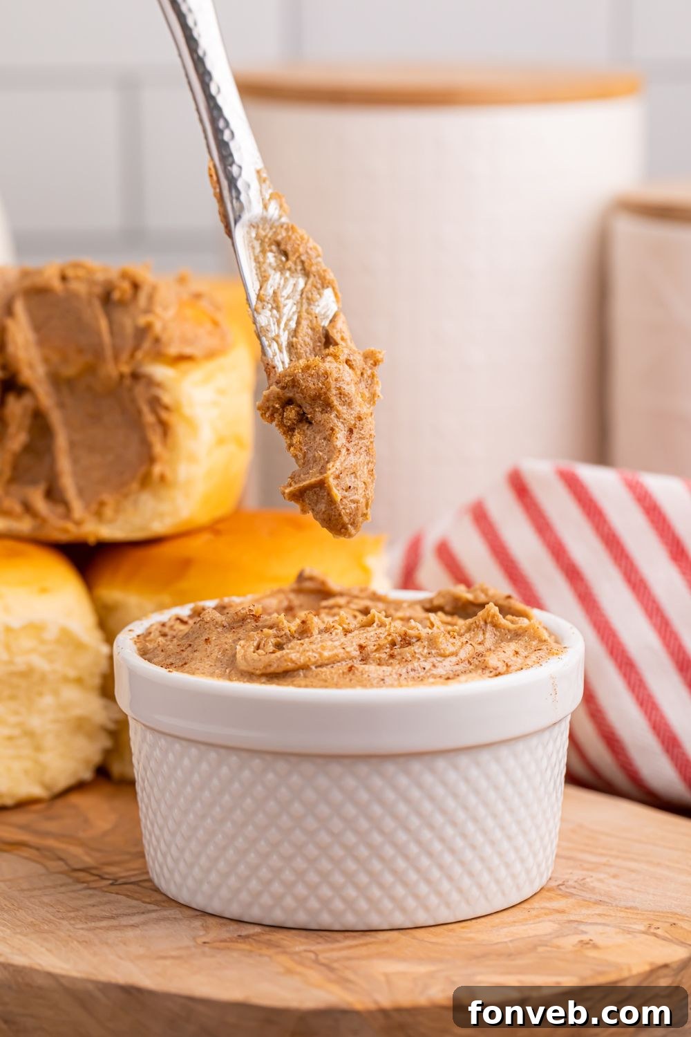 Brown Sugar Cinnamon Butter in a white container with a knife with some butter on it being lifted out of container 