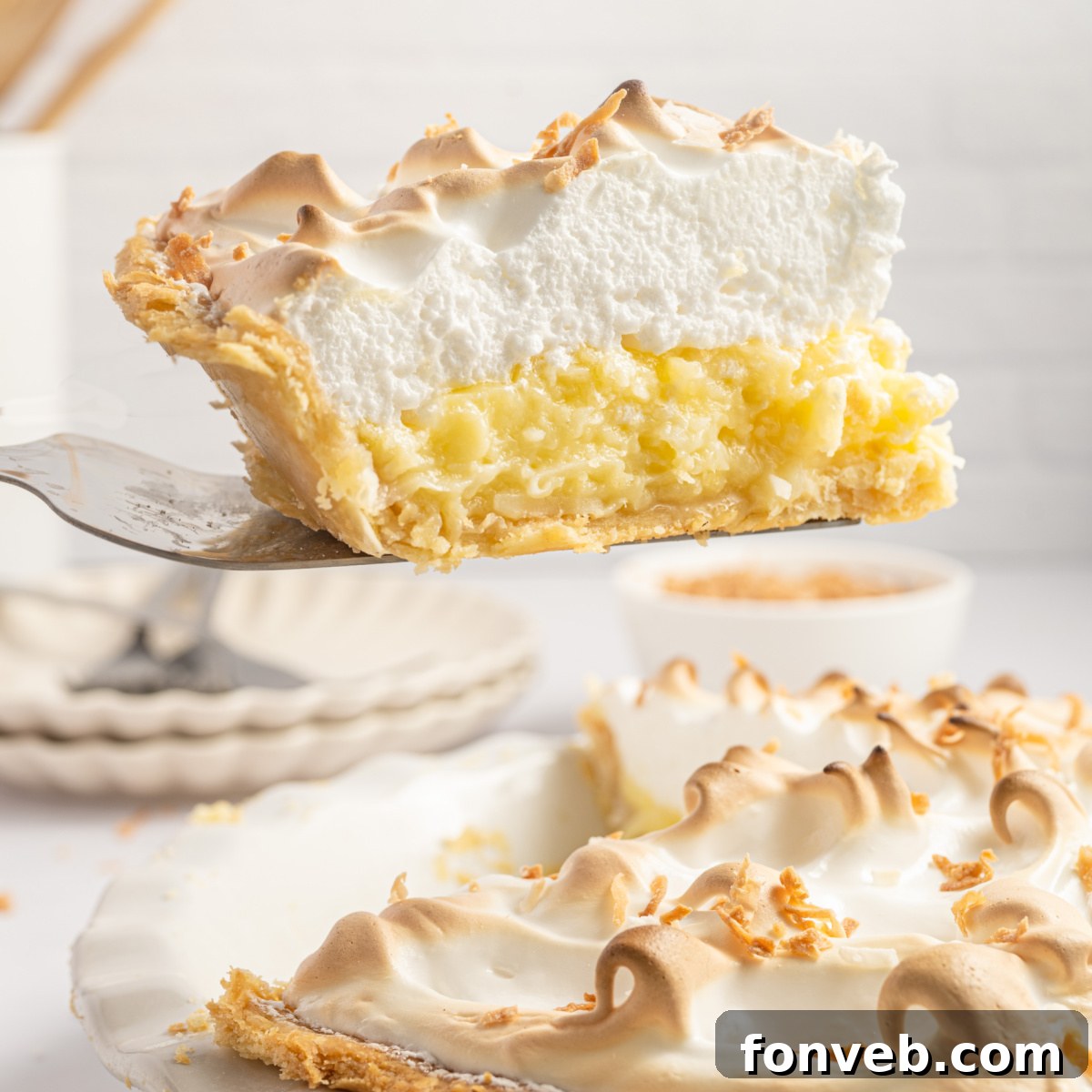 Coconut Meringue Pie in pie plate with a pie spatula lifting out a slice