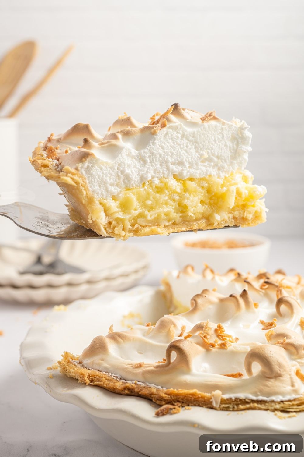 Coconut Meringue Pie in pie plate with a slice lifting out of the pie plate