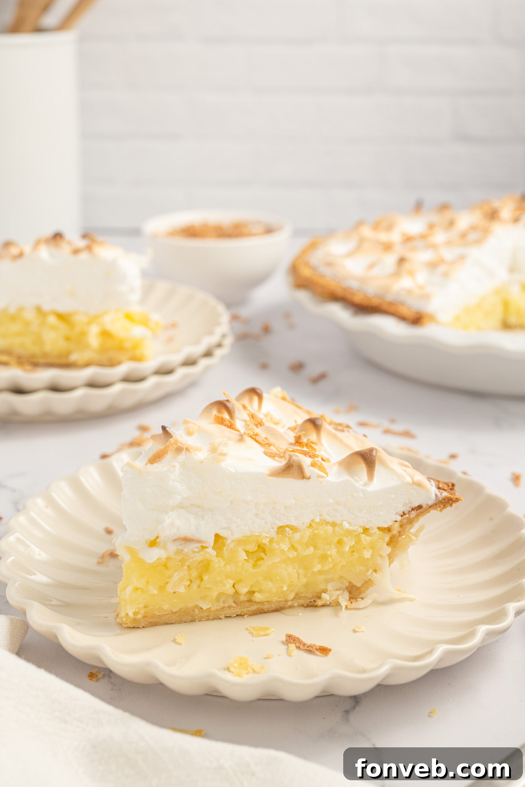 Coconut Meringue Pie on plate with toasted coconut sprinkled around it on table