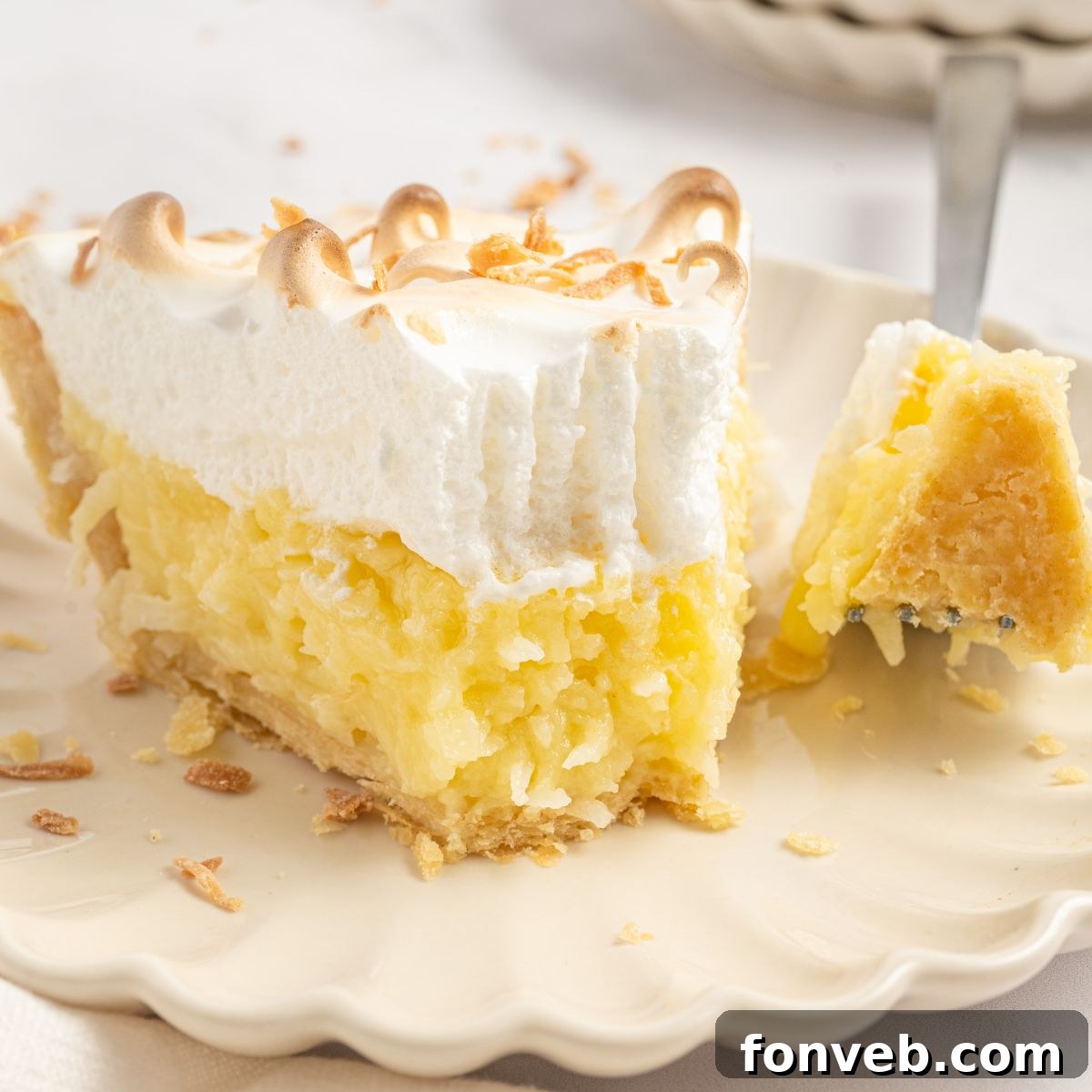 Coconut Meringue Pie on a plate with a fork with a bite on it