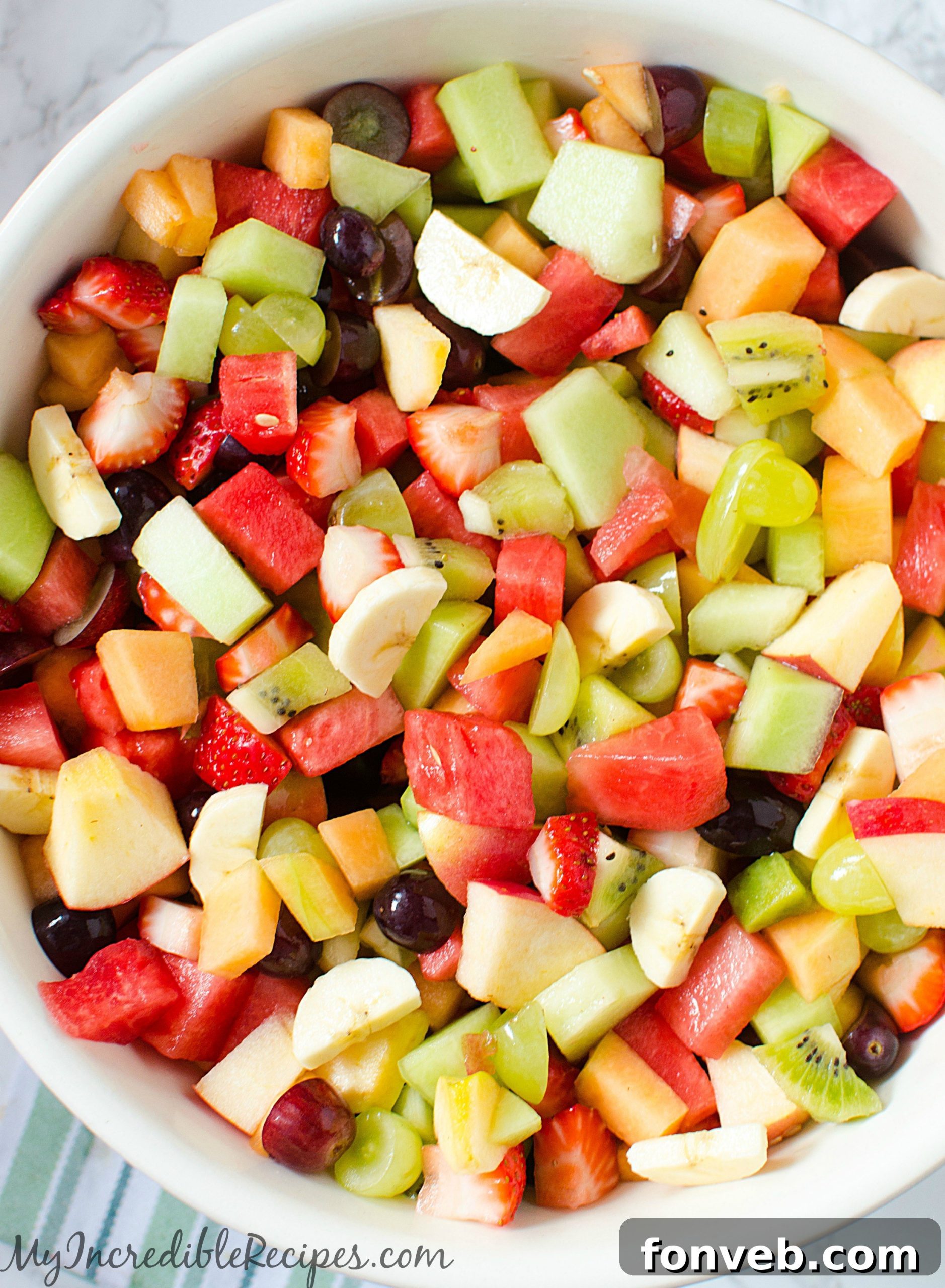 A vibrant bowl of Strawberry Kiwi Melon Fruit Salad, showcasing a colorful mix of fresh fruits like red strawberries, green kiwi slices, and orange melon cubes.
