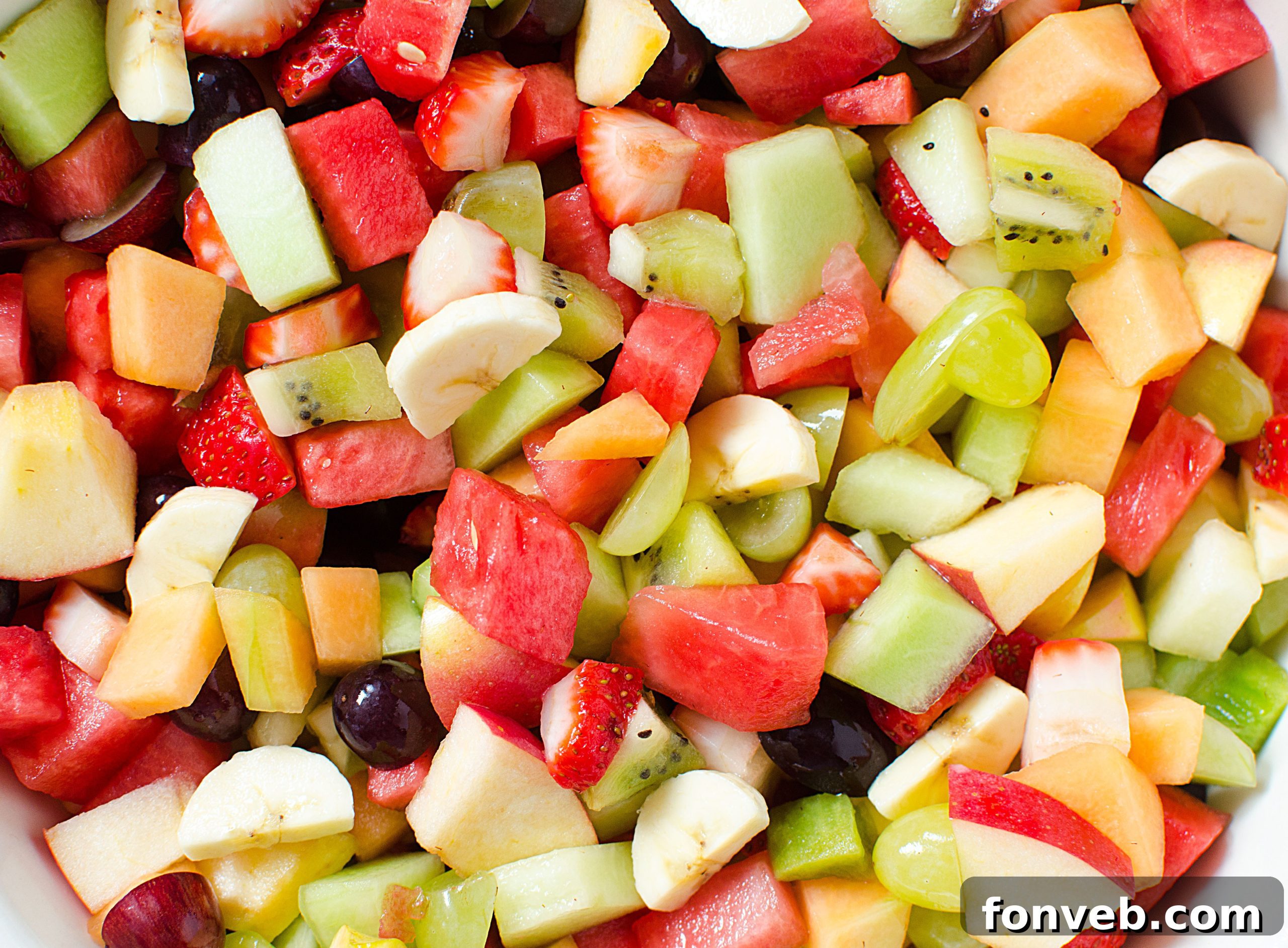 A delightful bowl of mixed fruit salad, glistening with glaze, ready to be served at a gathering.