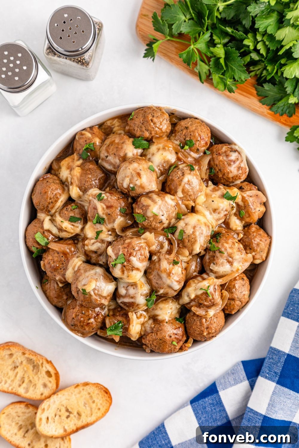 Crock Pot French Onion Meatballs in a bowl with some bread to the side of the bowl 