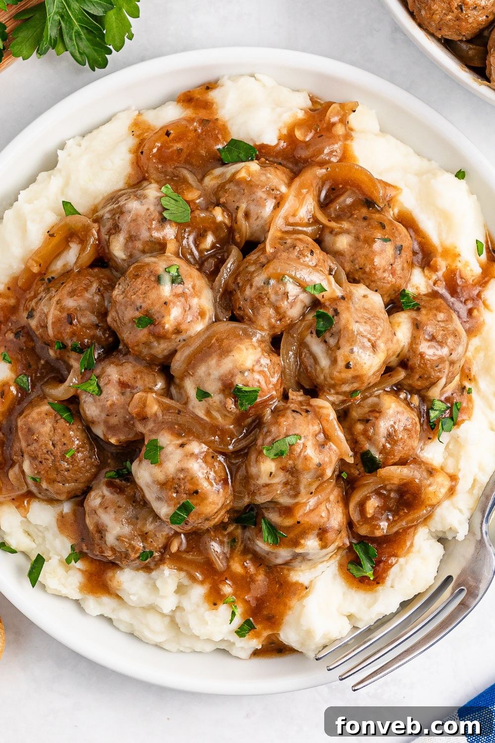 Crock Pot French Onion Meatballs on topped of mashed potatoes on a plate 