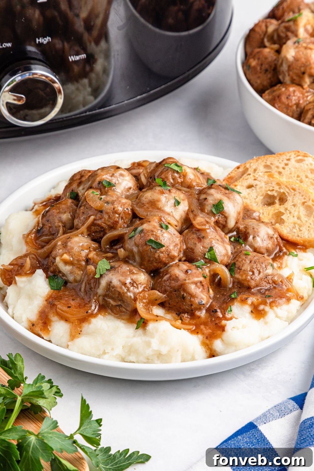 plate with mashed potatoes topped with meatballs, and a bread on side of plate 