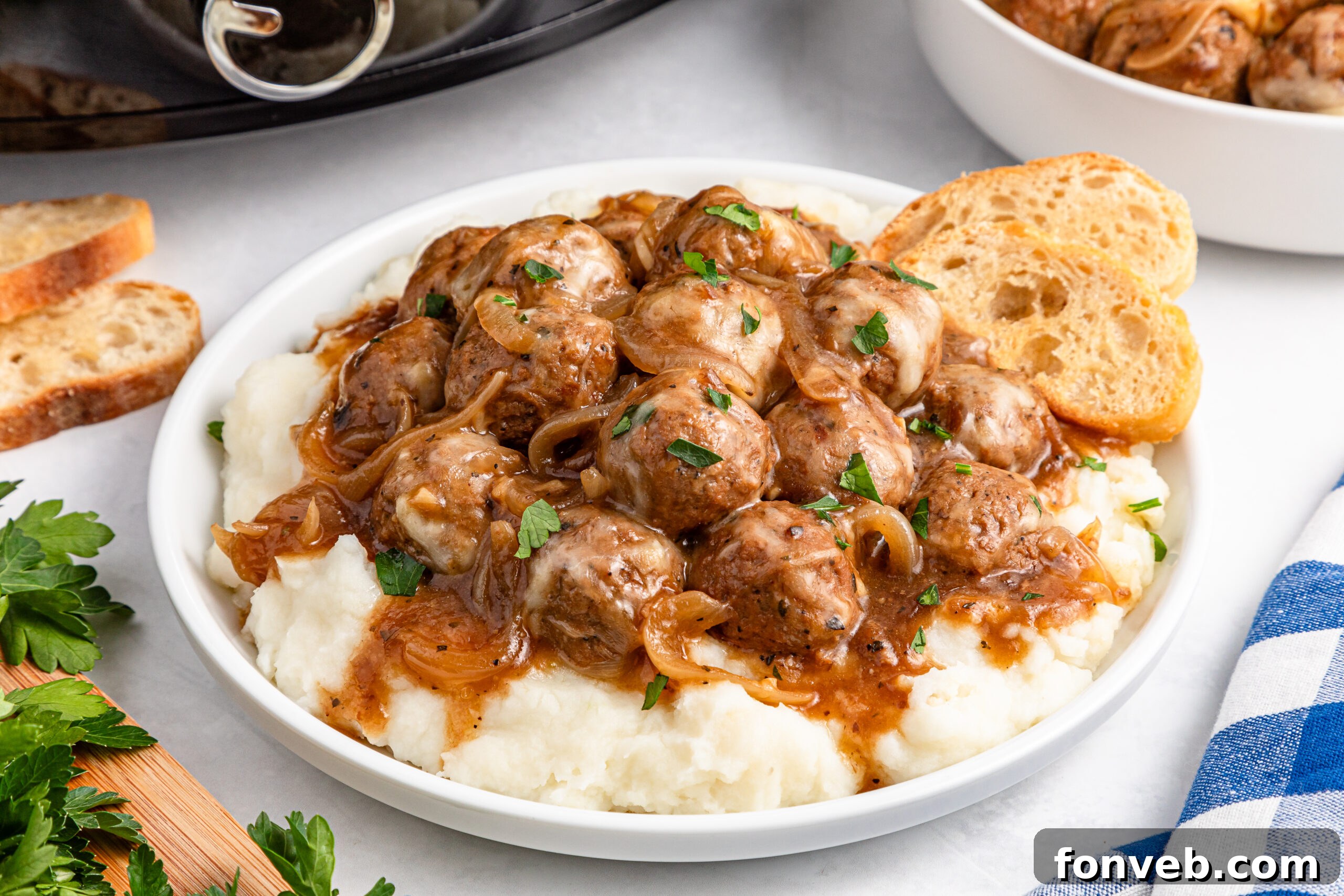 Crock Pot French Onion Meatballs on a white plate over mashed potatoes